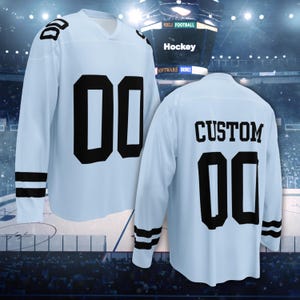 Puede incluir: Jersey de hockey de manga larga azul claro con detalles en negro. La camiseta muestra el n&uacute;mero "00" en letras negras grandes en la parte delantera y trasera. La parte trasera de la camiseta tambi&eacute;n tiene la palabra "CUSTOM" en letras negras.