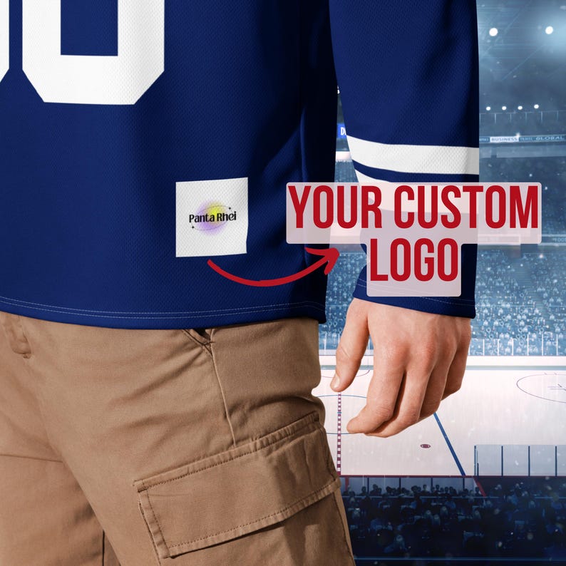 Puede incluir: Una camiseta azul de manga larga con rayas blancas en las mangas y un n&uacute;mero blanco. La camiseta tiene un &aacute;rea de logotipo personalizada y un parche que dice "Panta Rhei". La camiseta se usa con pantalones color caqui.