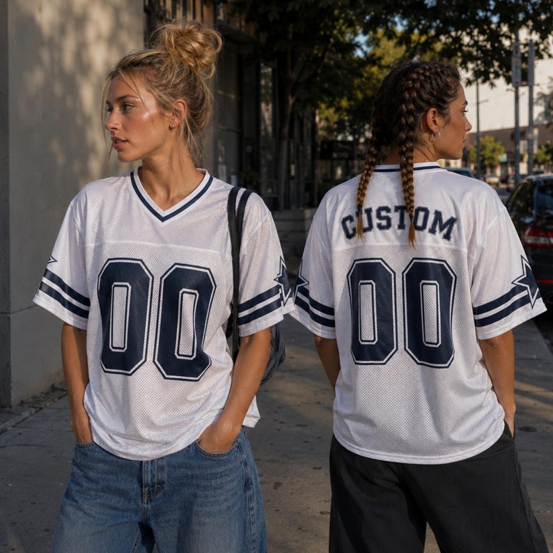 May include: A white mesh jersey with a V-neck, featuring dark blue stripes on the sleeves and a dark blue star. The front displays the number 00 in dark blue, while the back shows the word CUSTOM above the number 00 in dark blue lettering.