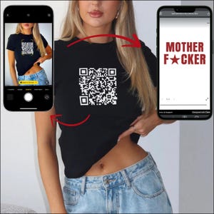 Puede incluir: Camiseta negra con un código QR blanco. La imagen muestra a una persona usando la camiseta, con un teléfono que muestra el texto "MOTHER F*CKER". La camiseta se combina con unos vaqueros azules.
