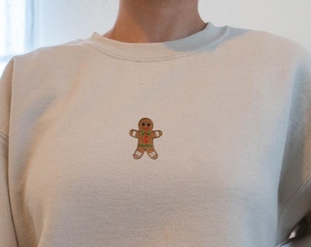Pode incluir: Uma camisa de moletom bege com um homem de gengibre bordado na frente.