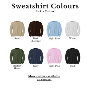 May include: Image showcasing a variety of sweatshirt colors. The image displays eight crewneck sweatshirts in different colors: sand, dark chocolate, light blue, white, military green, navy, light pink, and black. Text at the top reads "Sweatshirt Colours".