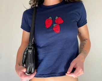 Op de afbeelding: Een kort marineblauw T-shirt met een afbeelding van drie rode aardbeien.