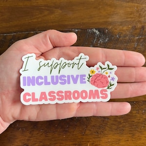 May include: White sticker with the text "I support inclusive classrooms" in green, purple, and pink lettering. A pink brain with green leaves and colorful flowers is on the right side of the sticker.