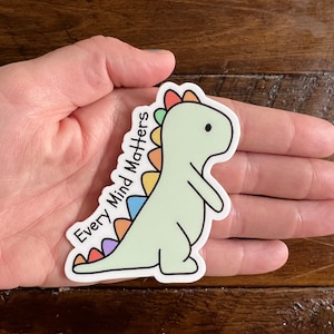 May include: A green dinosaur sticker with a rainbow colored spine and the text "Every Mind Matters".
