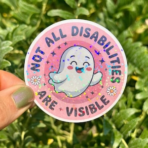 May include: A round sticker with the text "NOT ALL DISABILITIES ARE VISIBLE" in pink and white. The sticker features a smiling ghost illustration with a holographic effect, surrounded by stars and daisies.