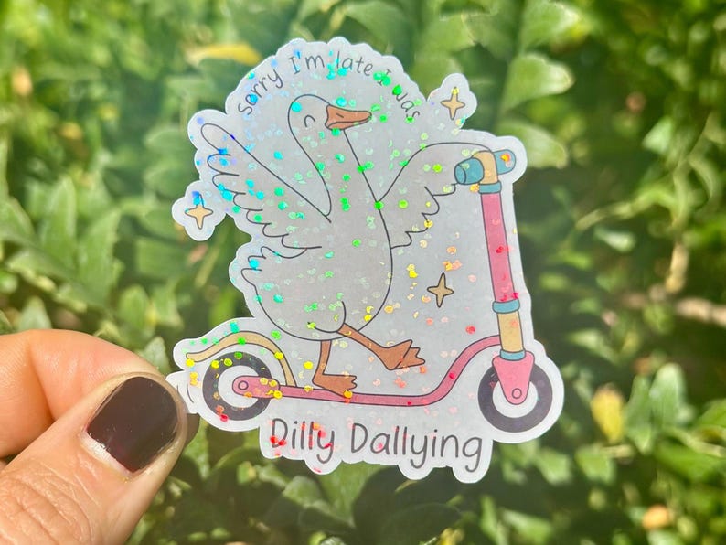 May include: A holographic sticker showing a cartoon goose on a pink scooter. The goose has its wings spread and the text reads "Sorry I'm late was dilly dallying". The sticker has a glitter effect and star details.