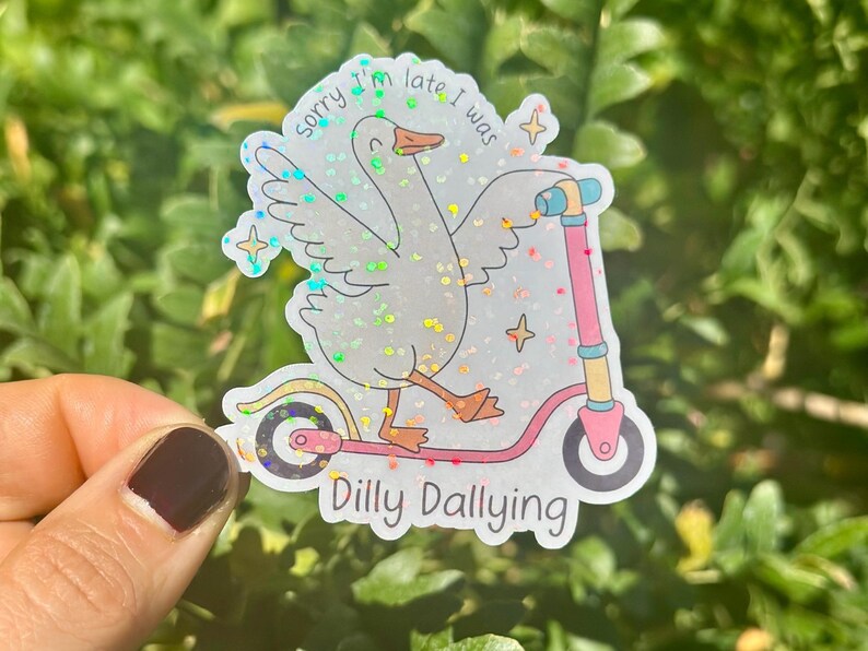 May include: A holographic sticker showing a goose on a pink scooter. The text reads "Sorry I'm late I was Dilly Dallying". The goose has its wings spread and is smiling. The sticker has a glittery effect.
