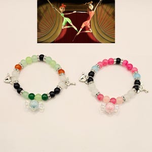 May include: Two bracelets with colorful beads, charms, and a key and heart pendant. The bracelets are on a white background.