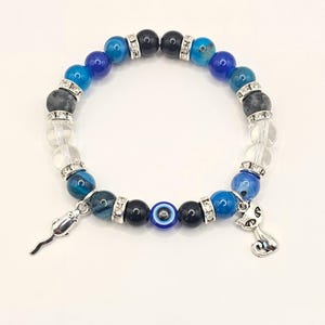 May include: A blue and black beaded bracelet with a silver charm of a cat and a silver charm of a mouse. The bracelet also features a blue evil eye bead.