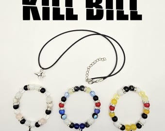 May include: Jewelry set featuring a black cord necklace with a star pendant and three beaded bracelets. The bracelets have various colored beads and charms. The text "KILL BILL" is displayed above the jewelry.