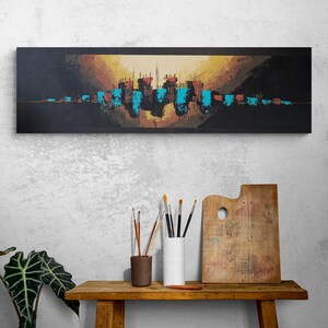 Peut inclure: Peinture abstraite de paysage urbain sur une toile rectangulaire noire. L'œuvre présente une ligne d'horizon avec des accents turquoise et orange sur un fond sombre. La peinture est exposée au-dessus d'une table en bois avec du matériel d'art.