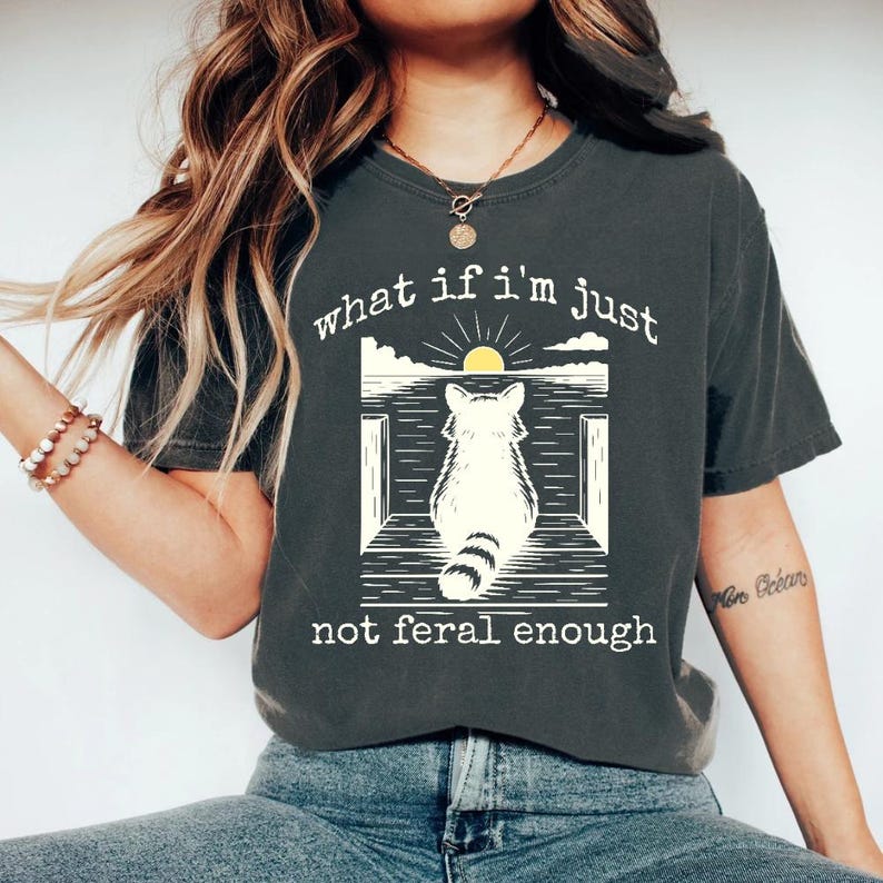 May include: A dark gray t-shirt with a graphic of a raccoon sitting on a porch with the text "what if i'm just not feral enough".