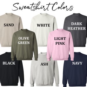 May include: A selection of ten different colored sweatshirts. The colors are: Sand, White, Dark Heather, Olive Green, Light Pink, Black, Ash, Navy.