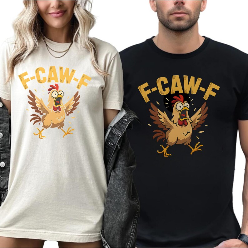 May include: Two t-shirts, one cream and one black, each featuring a cartoon chicken with outstretched wings and the text "F-CAW-F" in gold. The chicken is brown, with a red comb and yellow feet.