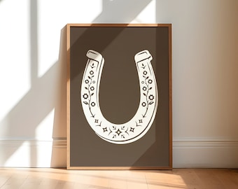 May include: A brown framed print with a white horseshoe design. The horseshoe is decorated with a floral pattern.