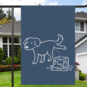 May include: A navy blue garden flag features a white cartoon dog urinating on a melting ice cube. The flag is displayed on a black metal stand in front of a house with a green lawn and blue sky.