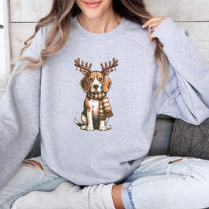 May include: A gray sweatshirt with a cartoon beagle wearing a scarf and antlers. The beagle is brown and white with a black nose.