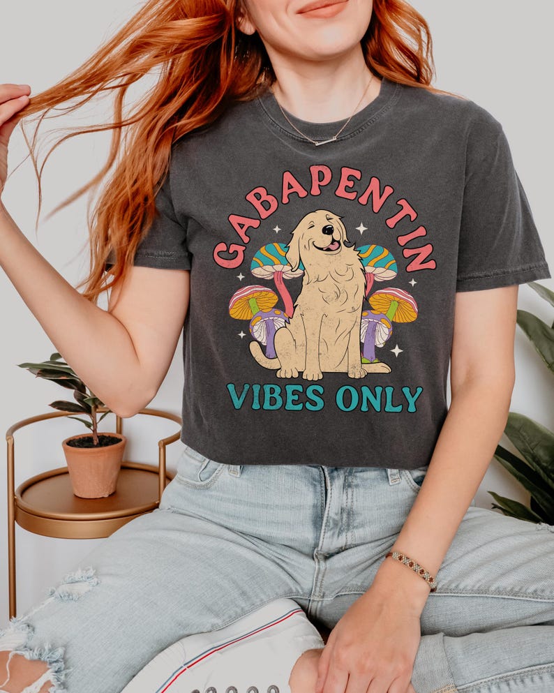 K&ouml;nnte beinhalten: Ein schwarzes, bauchfreies T-Shirt mit einem Aufdruck eines Golden Retrievers, der vor Pilzen sitzt. Der Text "Gabapentin Vibes Only" ist auf dem Shirt gedruckt.