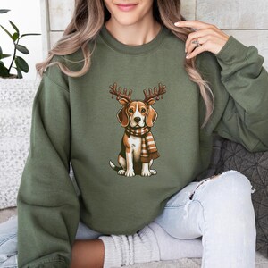 May include: A green sweatshirt with a beagle dog wearing a scarf and reindeer antlers. The dog is sitting and looking to the right.