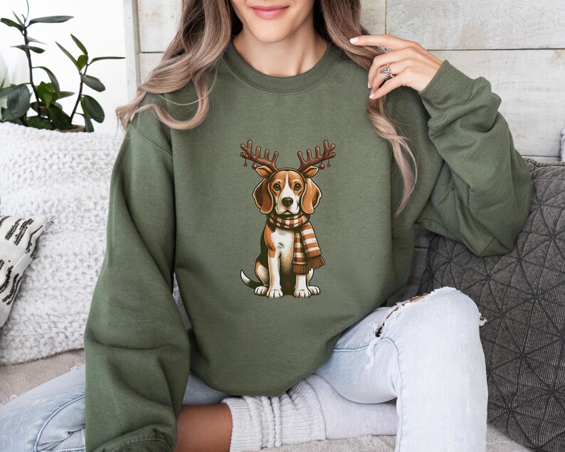 May include: A green sweatshirt with a beagle dog wearing a scarf and reindeer antlers. The dog is sitting and looking to the right.