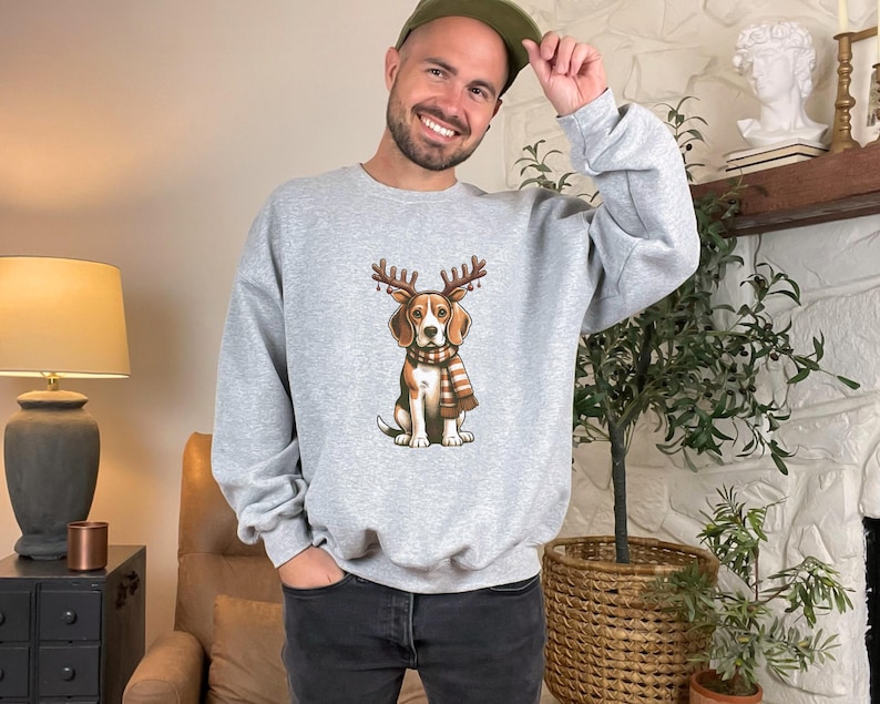 May include: A gray sweatshirt with a cartoon beagle wearing a scarf and antlers. The beagle is wearing a red and white scarf and has a brown nose and brown eyes.