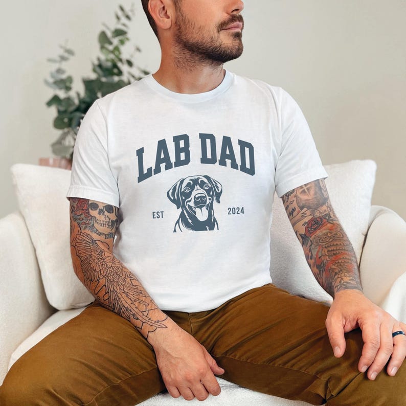 May include: White t-shirt with a blue graphic of a Labrador Retriever and the text "Lab Dad Est 2024".