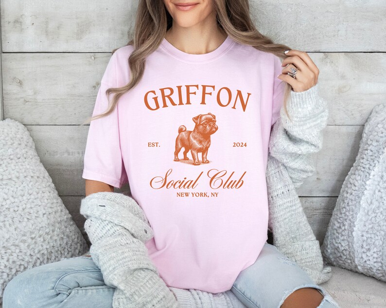 May include: Pink t-shirt with a brown graphic of a Griffon dog and the text "Griffon Social Club Est. 2024 New York, NY"