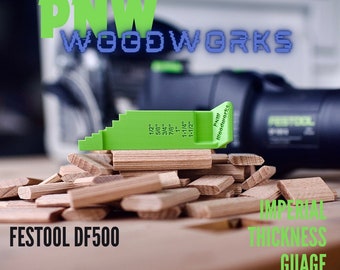 Puede incluir: Una galga de espesor imperial de plástico verde con marcas de 1/2 pulgada a 1 1/2 pulgadas. La galga está apoyada en una pila de bloques de madera. El texto "PNW Woodworks" está impreso en la galga. El texto "FESTOOL DF500" está impreso en la mesa debajo de la galga.