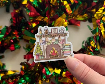 May include: A sticker featuring a cozy Christmas fireplace scene with stockings, a Christmas tree, and books. The sticker has a warm color palette with a fireplace, stockings, and a Christmas tree. The text on the sticker reads "Tis the season to be reading."