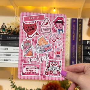 May include: A pink and white checkered sticker sheet with various illustrations and text, including a devil heart, lips, and the words "Smut St" and "Good Girl". The sheet also features a warning about explicit content.