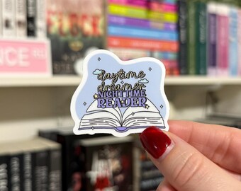 May include: A blue and white sticker with a book and the text "daytime dreamer nighttime reader" with stars and clouds.