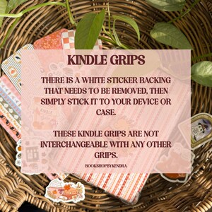 May include: A selection of Kindle grips featuring diverse designs, such as autumnal illustrations and patterns. The grips are presented in a woven basket with green leaves. The image includes the text "Kindle Grips".