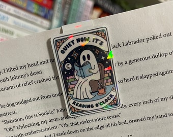May include: A holographic bookmark featuring a ghost reading a book in a chair with the text "Quiet Now, It's Reading O'Clock".