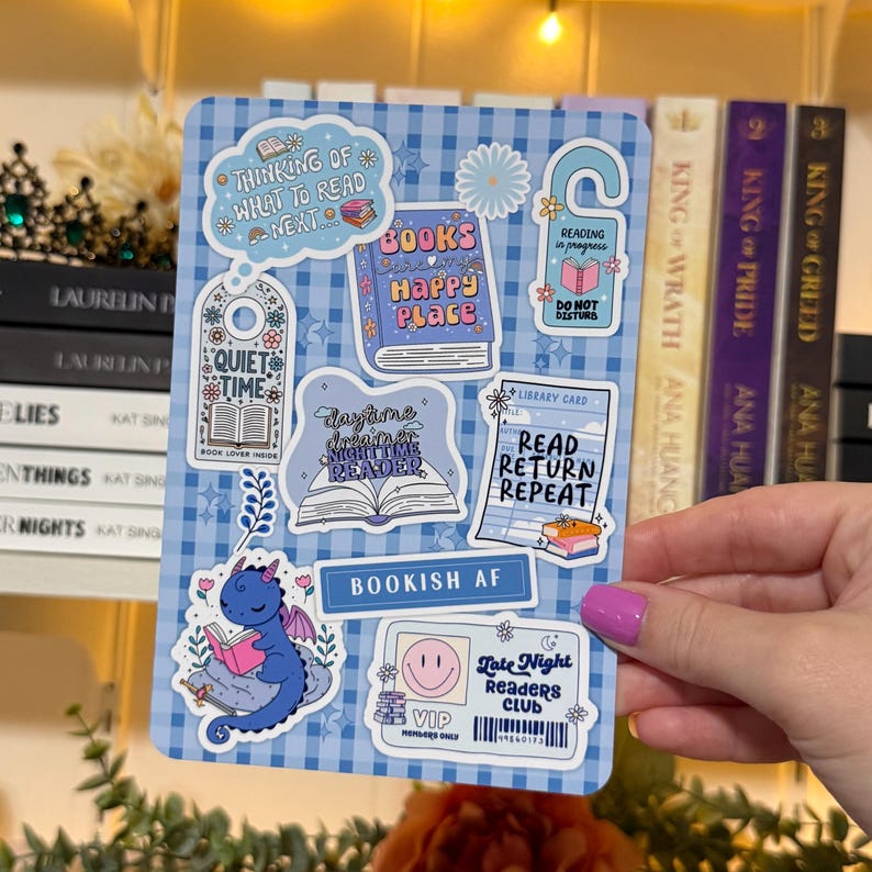 May include: A blue and white sticker sheet with various book-themed designs. Includes stickers with phrases like "Quiet Time," "Books Happy Place," and "Read Return Repeat." A blue dragon reading a book is also featured.