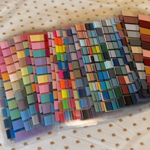 May include: A set of color swatches organized in rows and columns. The swatches are arranged in a rainbow pattern, with shades of red, orange, yellow, green, blue, indigo, and violet. The swatches are made of a smooth, textured material.