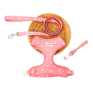May include: Pink dog harness with white hearts, matching pink leash and collar with white hearts and the text "Pup Mommy" on the collar and harness.