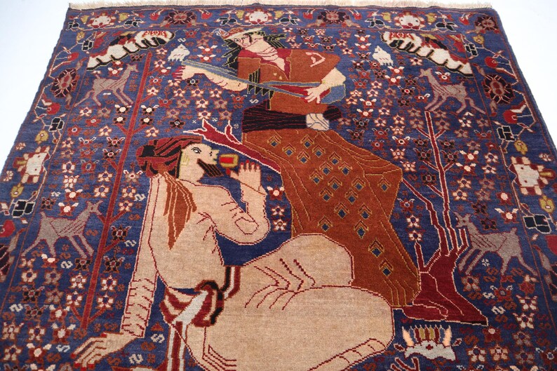 May include: A detailed, hand-woven rug with a deep blue background. The rug features stylized figures in shades of tan, brown, and red, with intricate floral and animal motifs. The design includes deer and trees, creating a rich, artistic tapestry.