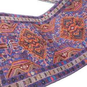 May include: A traditional Persian rug with a blue background and intricate patterns in shades of red, orange, and green. The rug features a central medallion and a border with geometric designs.