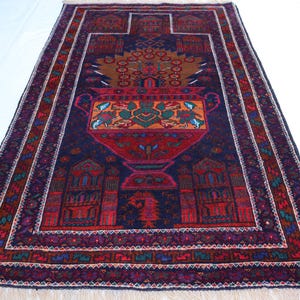 May include: A traditional Persian rug with a dark blue background and intricate floral and geometric patterns. The rug features a central design of a vase with flowers and leaves, surrounded by a border of repeating motifs.