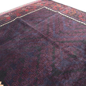 May include: A dark blue rug with a geometric pattern in shades of red, white, and black. The rug has a fringe border.
