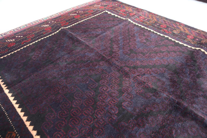 May include: A dark blue rug with a geometric pattern in shades of red, white, and black. The rug has a fringe border.