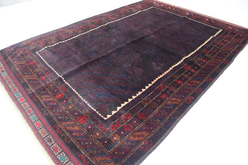 May include: A dark blue rug with a detailed, intricate pattern in shades of red, brown, and green. The rug has a central field with a border of geometric designs.