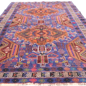 May include: A vintage rug with a blue background and intricate geometric patterns in shades of orange, red, green, and brown. The rug has a fringe border.