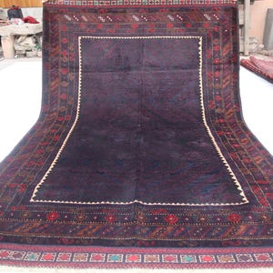 May include: A dark blue rug with a detailed, intricate pattern in shades of red, brown, and cream. The rug has a fringe border.
