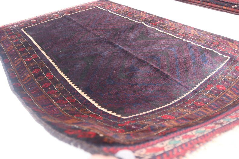May include: A dark blue rug with a cream-colored border and intricate red, brown, and blue patterns. The rug has a traditional design and is made of wool.