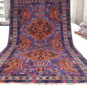 May include: A traditional Persian rug with a vibrant blue background and intricate geometric patterns in shades of red, orange, and green. The rug has a central medallion and a border with floral motifs.