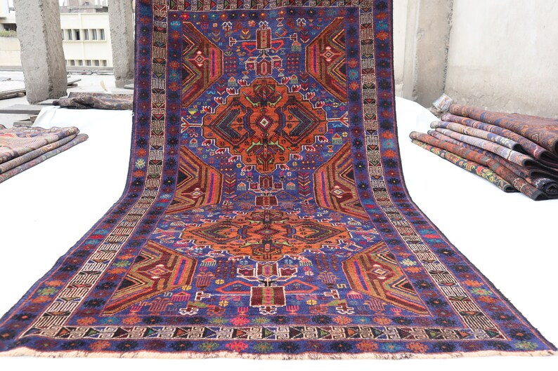 May include: A traditional Persian rug with a vibrant blue background and intricate geometric patterns in shades of red, orange, and green. The rug has a central medallion and a border with floral motifs.