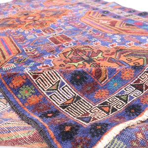 May include: A vintage Turkish rug with a blue background and intricate geometric patterns in shades of orange, red, green, and black. The rug has a fringe border and is folded in half.
