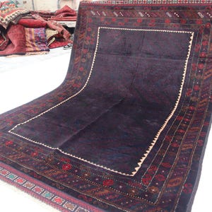 May include: A dark blue rug with a detailed floral pattern in shades of red, brown, and cream. The rug has a large central square with a smaller square inside, creating a frame effect.